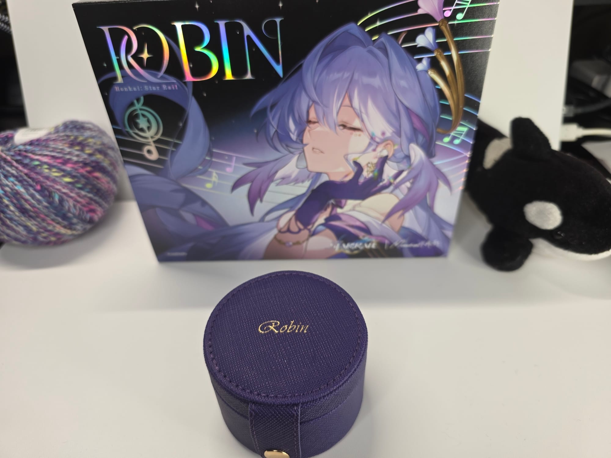 Moondrop Robin in its purple outer case sitting in front of the retail box. A ball of purple yarn and a stuffed Shamu killer whale are pictured but are not included in the package.