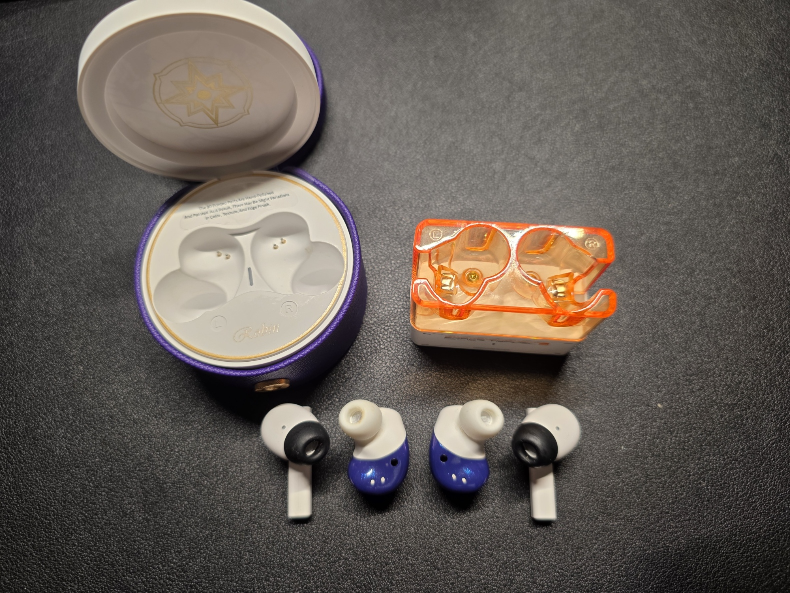 The Moondrop Robin are pictured faceplates down on a black desk with the Space Travel 2 pictured to their left and right.
