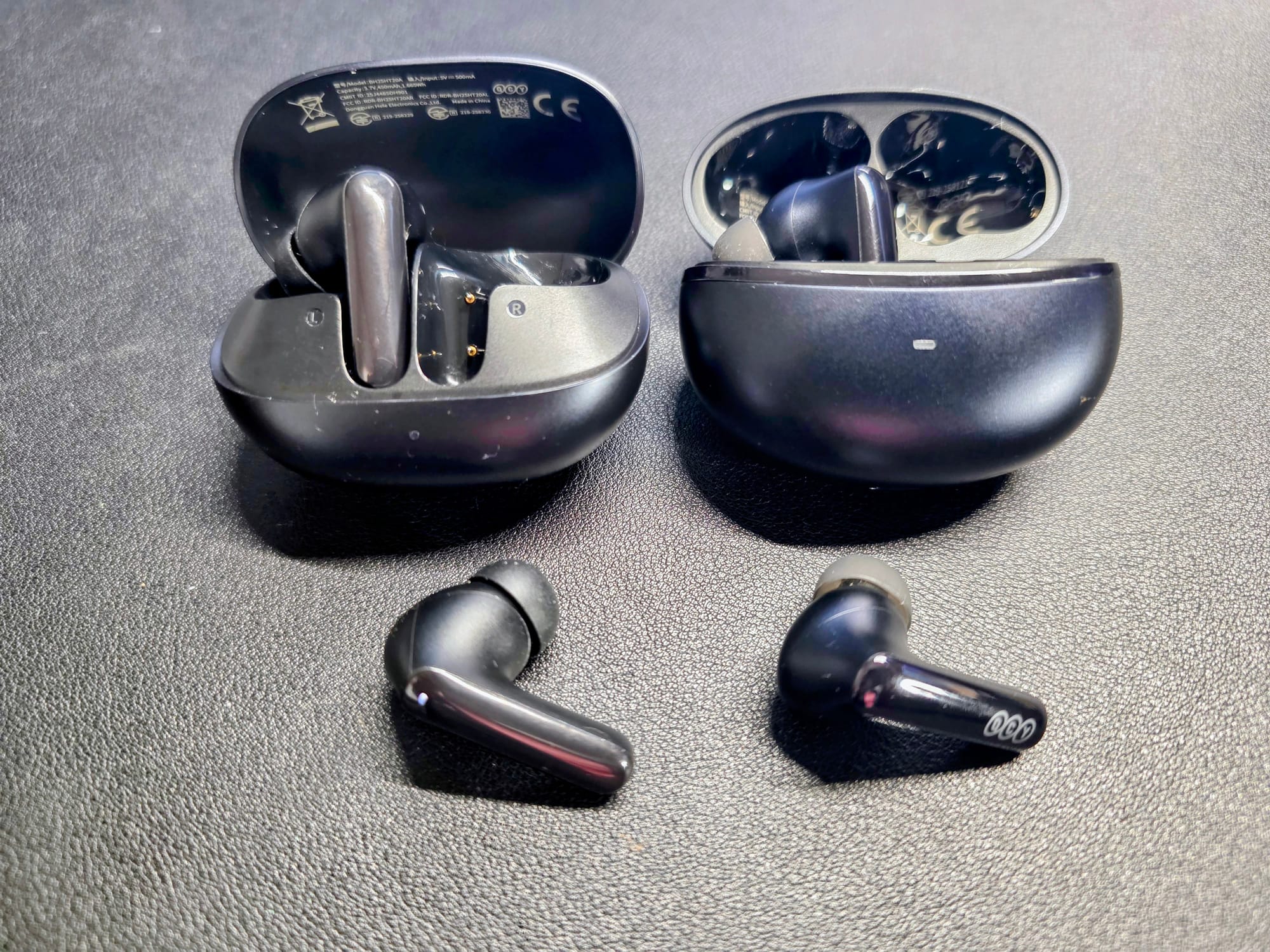 MeloBuds N20 (left) and N70 (right) outside of their cases with one bud lying in front of each case