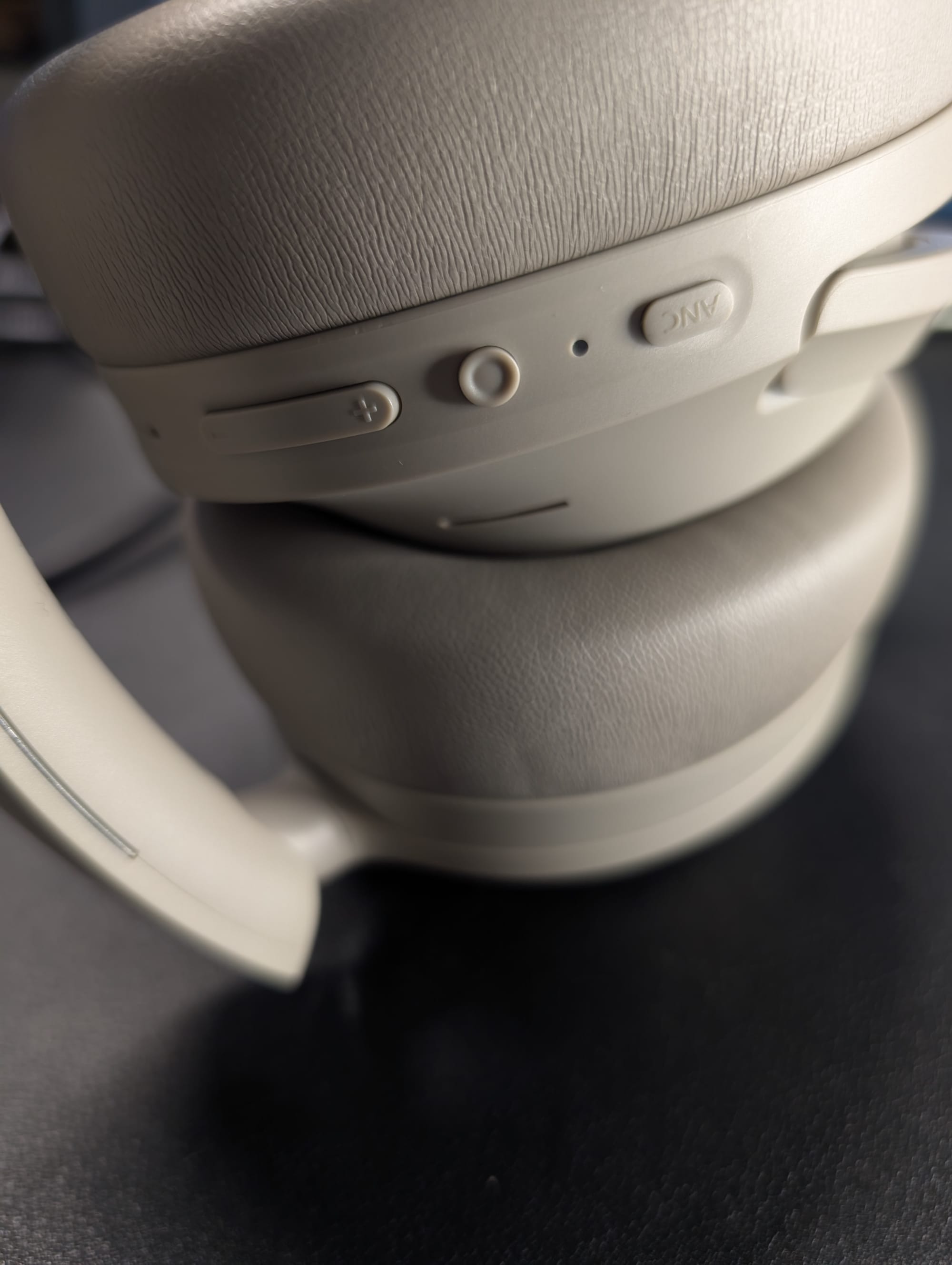 The photo shows the buttons from left to right: volume rocker, pairing/power button, ANC modes