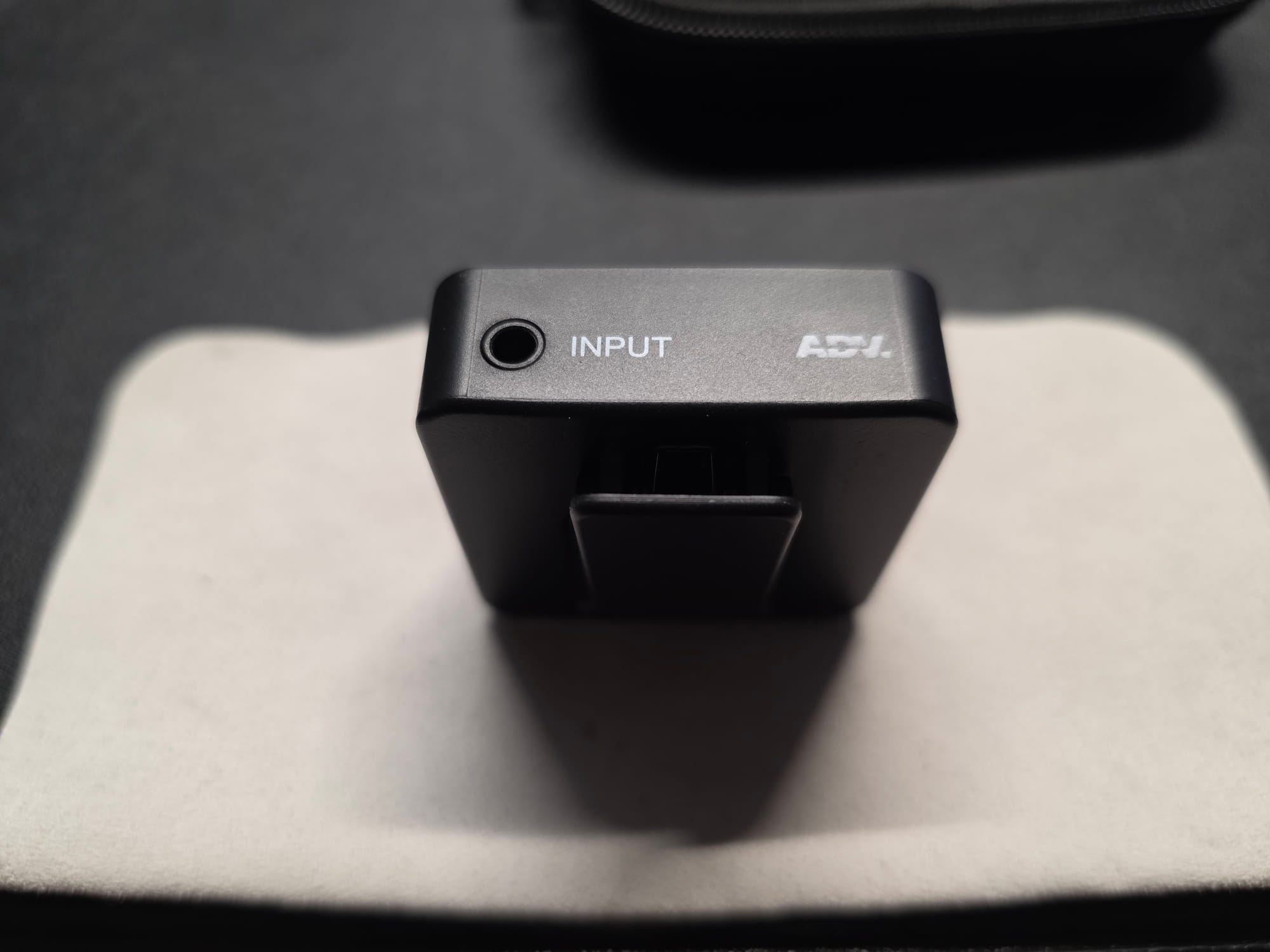 The Accessport Pro with aux jack displayed. It is standing on its top on a white microfiber cloth on a black desk.