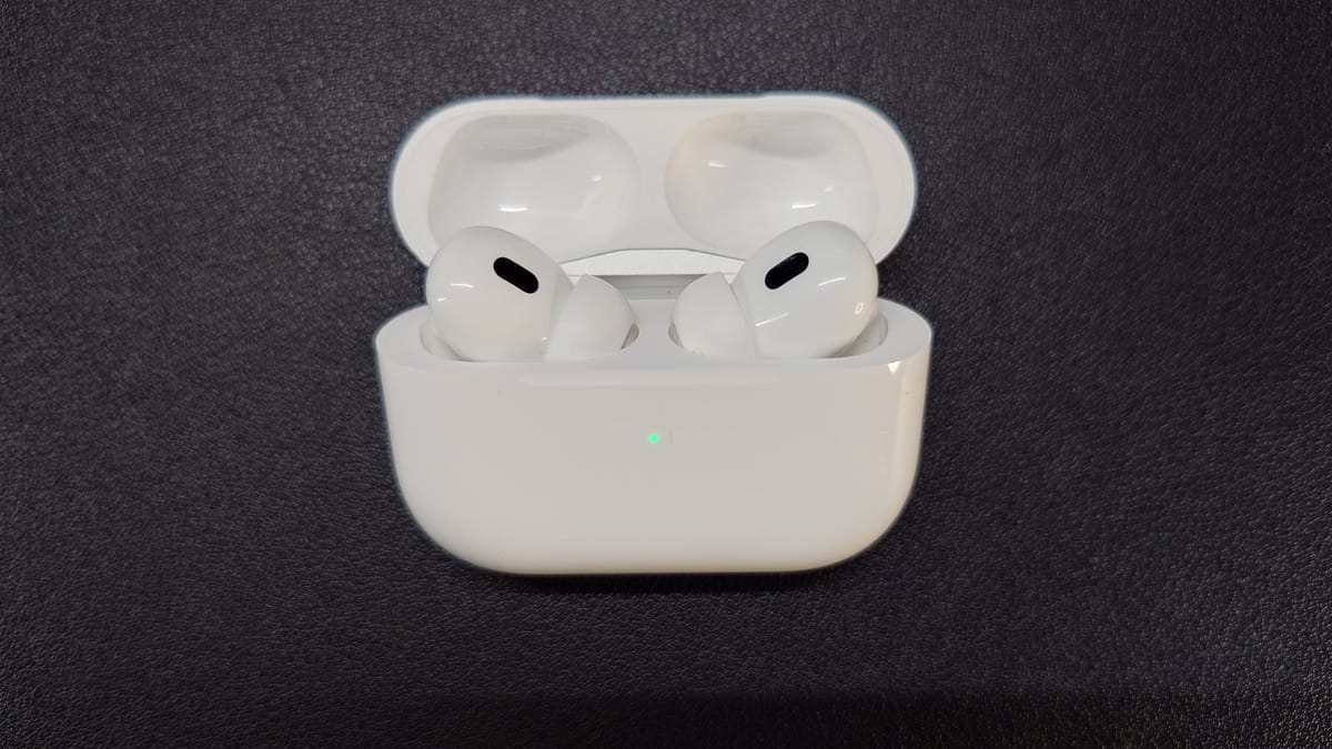AirPods Pro 2 in their charging case, which is open, and the green light indicates high battery level