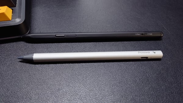 Samsung S Pen Pro and Penoval USI 2.0 on a desk. The S Pen is black and the Penoval is silver with a visible USB-C port.