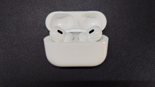AirPods Pro 2 in their charging case, which is open, and the green light indicates high battery level