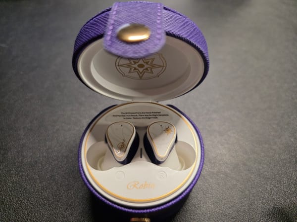 The Moondrop Robin earphones are pictured in their case and the purple outer case.  The case is open and the white earphones are visible.